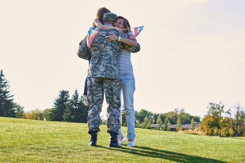 Military man father hugs daugther and wife.