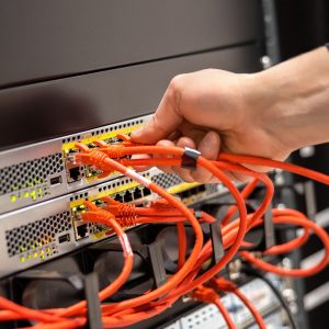 Close-up of Male Technician Plugging Network Cable In Network Router