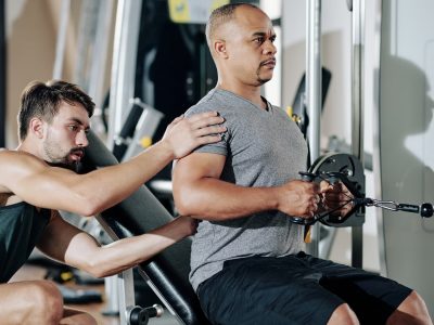 Personal trainer controlling exercising man